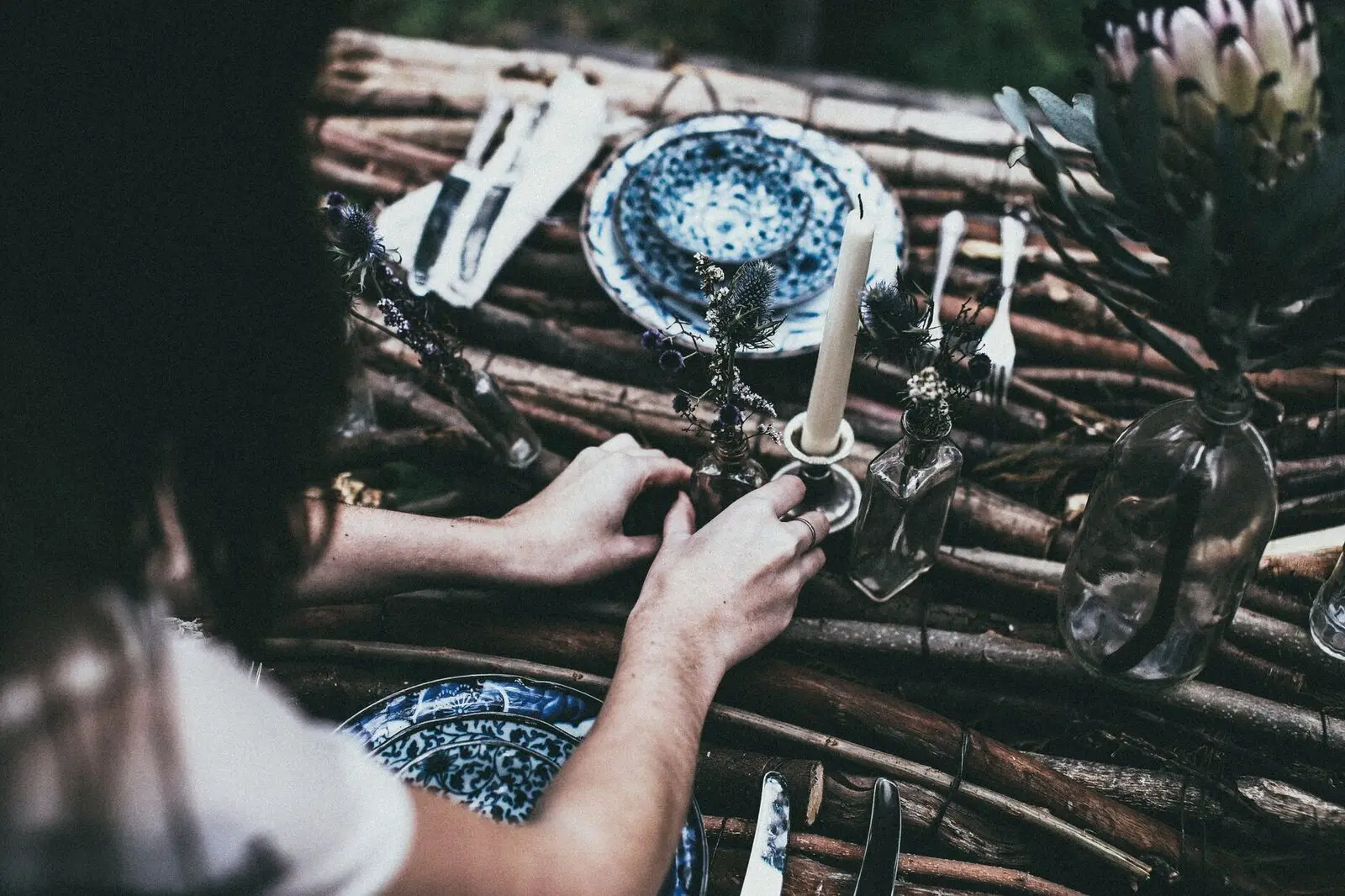 Hands laying a blue-patterned plate on a wooden table